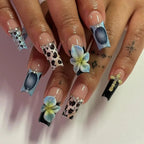 Close-up of hands with intricately designed nails featuring flowers and patterns.