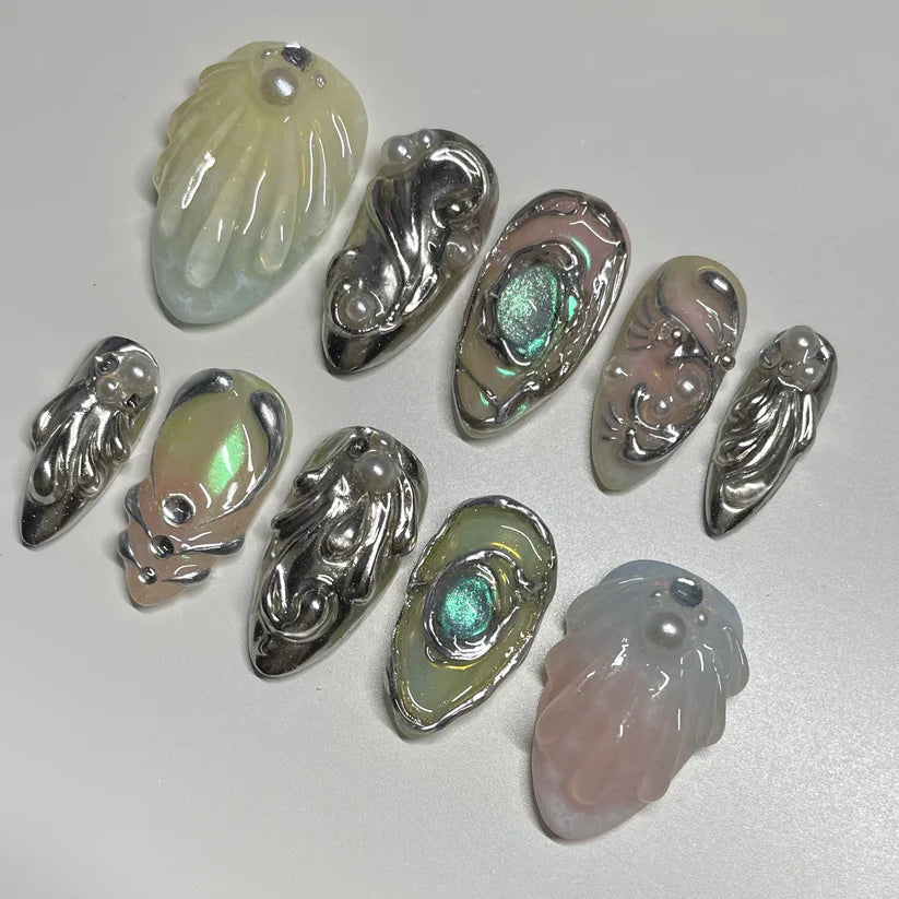 Collection of silver and gemstone jewelry nails on a light gray background