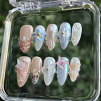 Decorative false nails in a clear case with a blurred green background