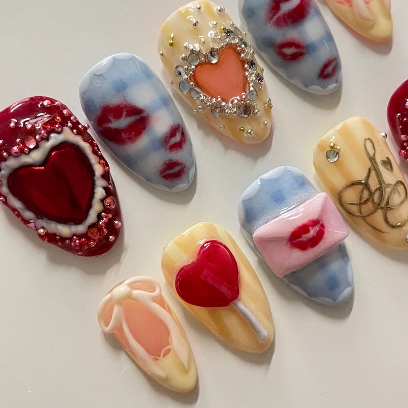 Decorative nail art designs with hearts, lips, and other embellishments on a white background.