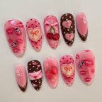 Decorative nail art with pink and brown designs on a light gray background