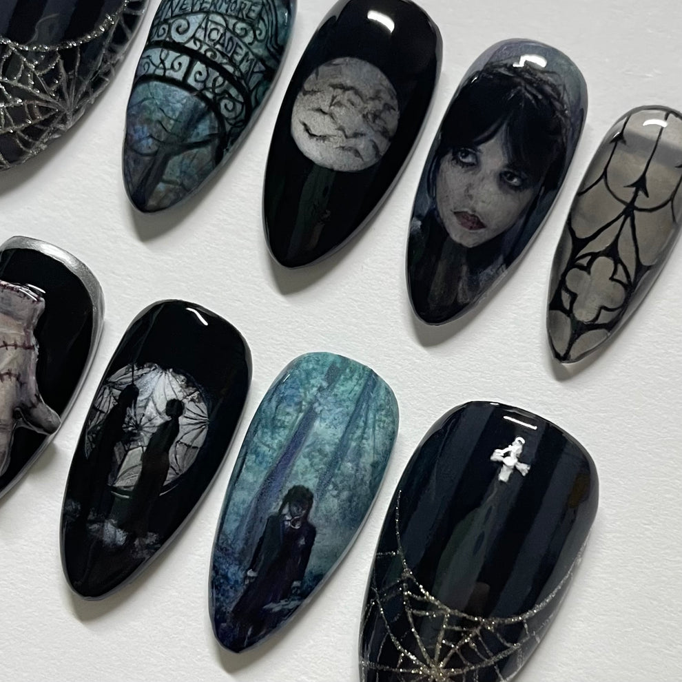 Gothic-themed nail art designs on black nails with intricate patterns and images.
