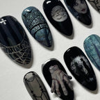 Gothic nail art designs on black nails with intricate patterns and a white background.