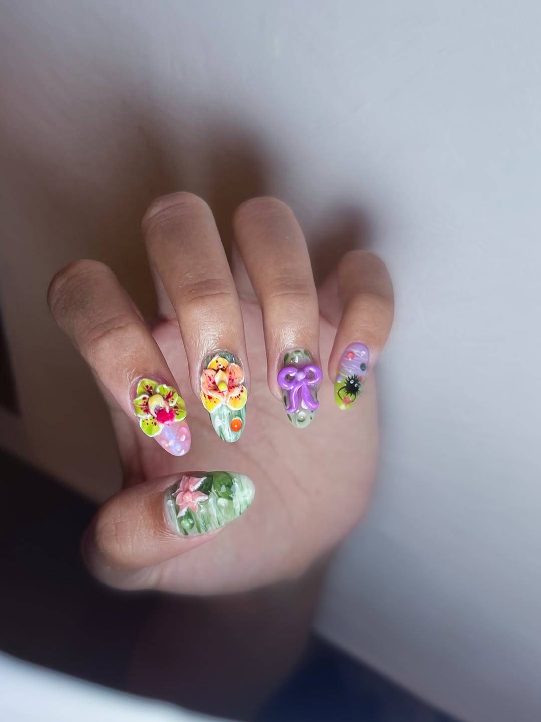 Hand with colorful floral nail art on a plain background