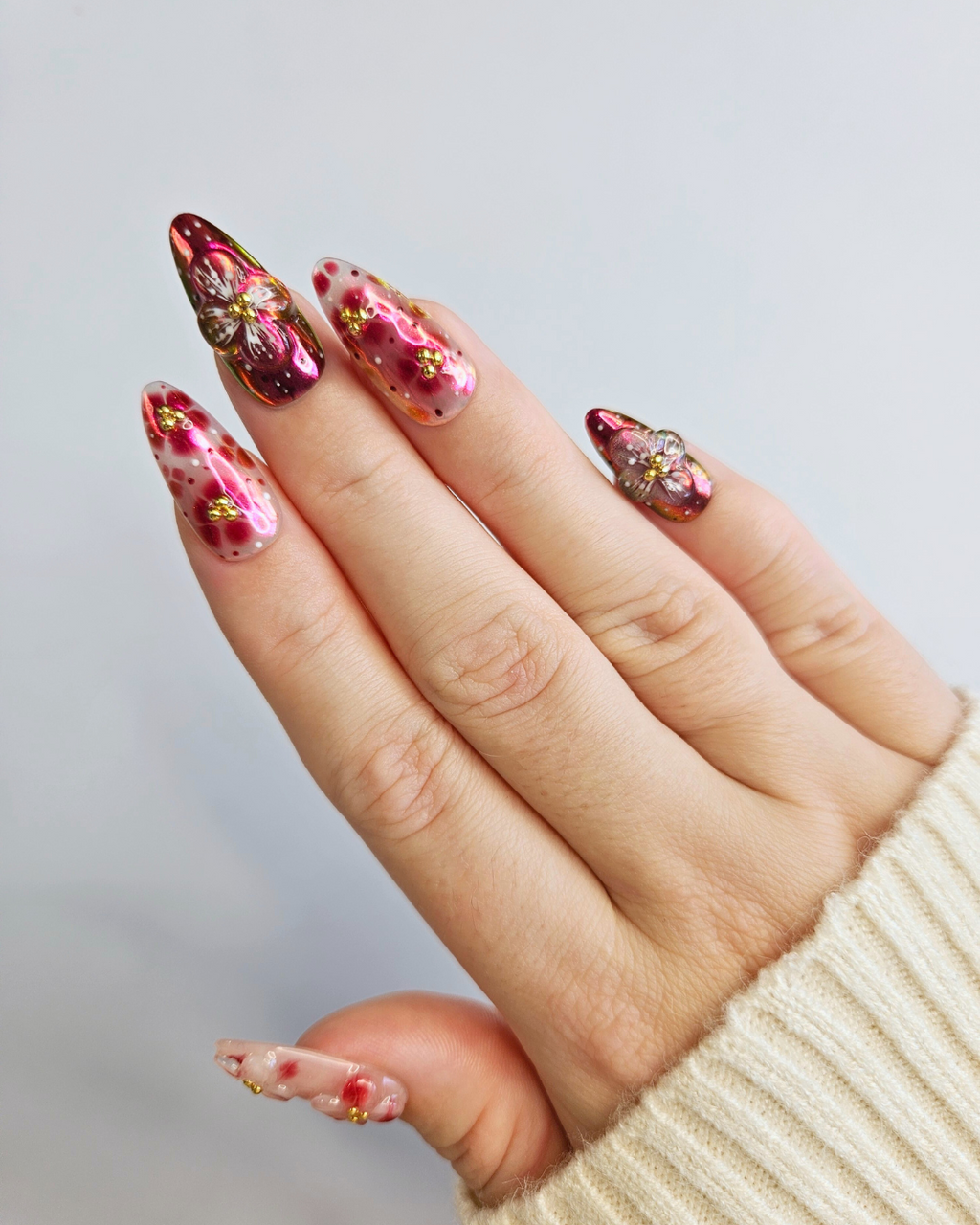 Hand with decorative nail art on a plain background