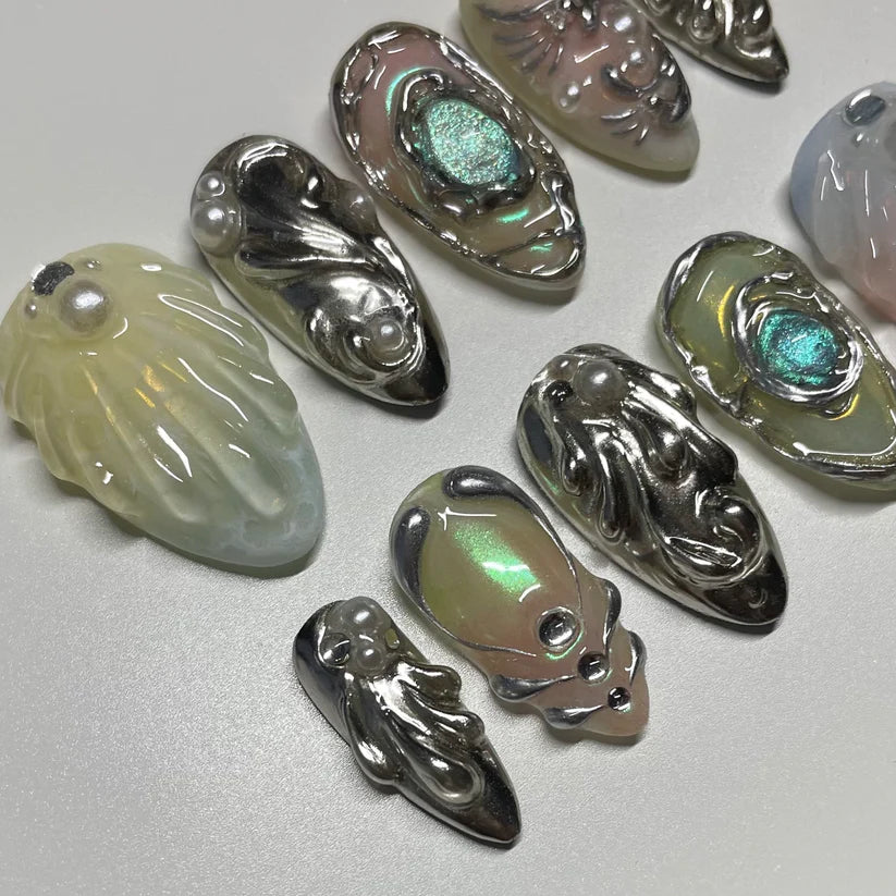 Metallic leaf-shaped nails with reflective surfaces on a light gray background