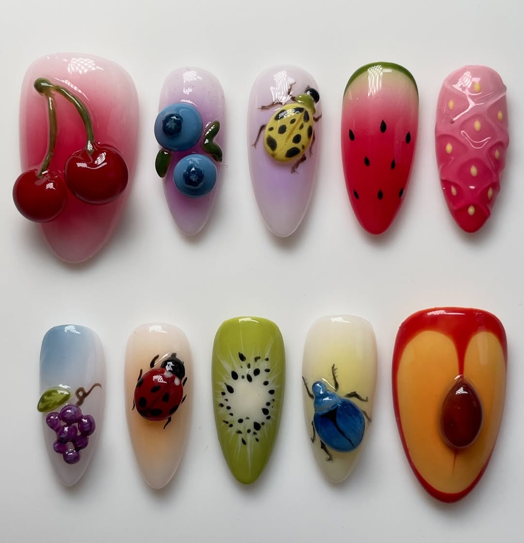 Nail art designs of fruits and insects on a white background