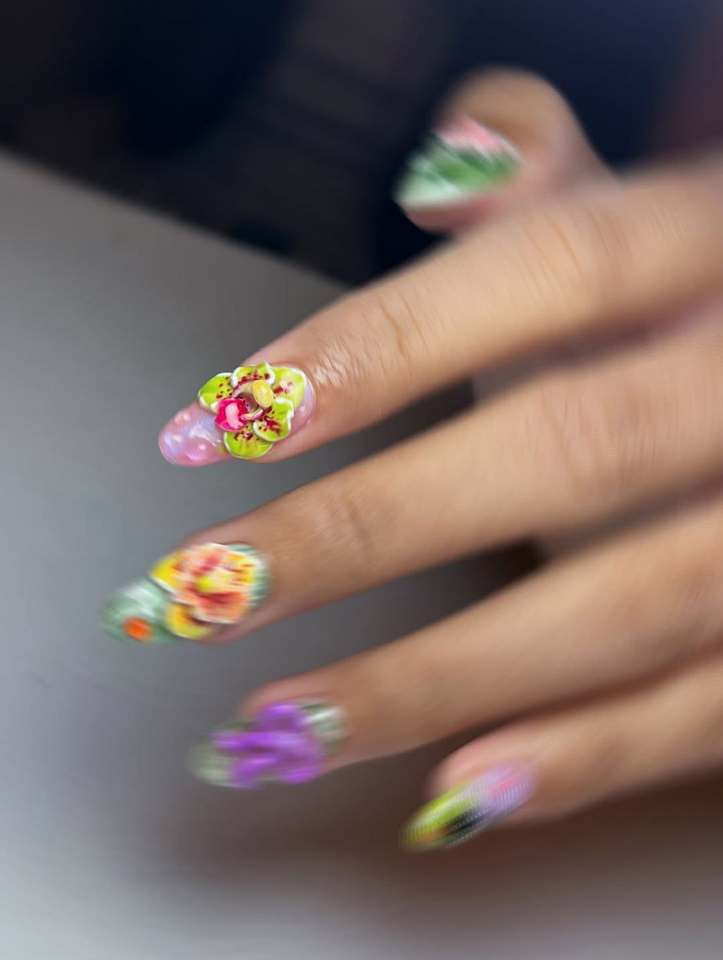 Close-up of a hand with colorful floral nail art on a neutral background