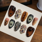 Set of artistic nail art designs on a white card with a wooden surface background