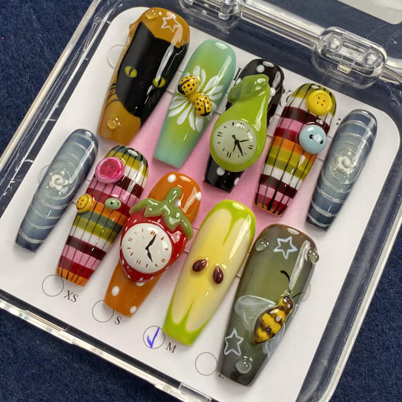 Set of colorful nail art designs in a clear case on a dark blue fabric background