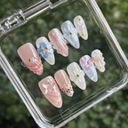 Set of decorative nail art designs in a clear case with a green leafy background