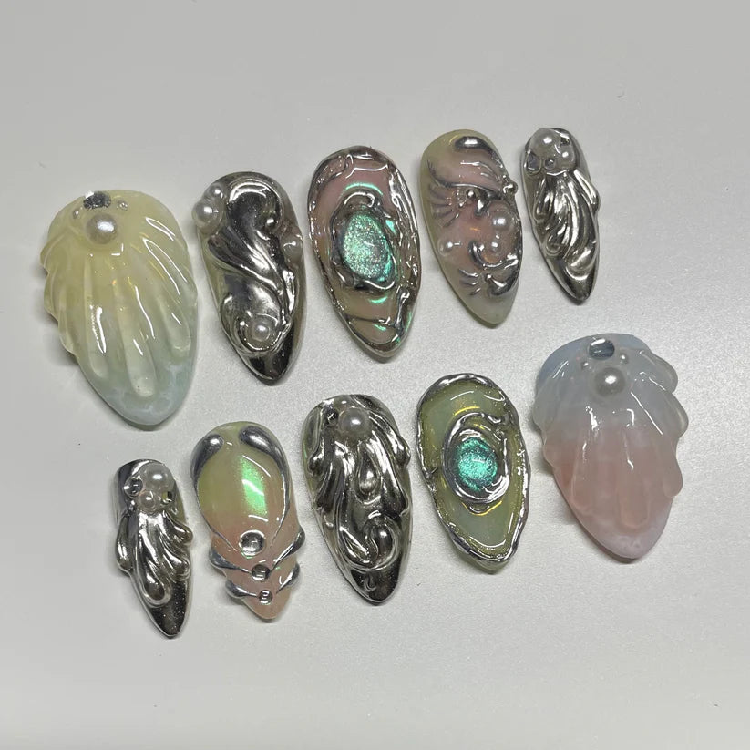 Set of metallic and semi-translucent shell-shaped nails on a light gray background